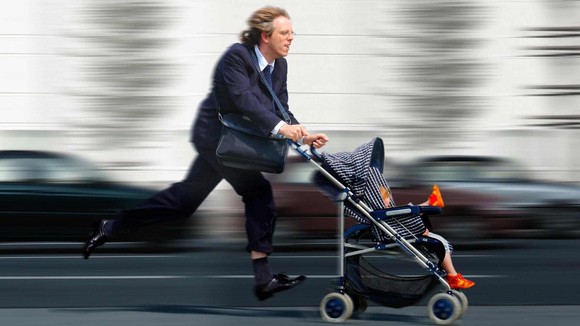 Vater rennt mit Kind im Kinderwagen zur Arbeit.